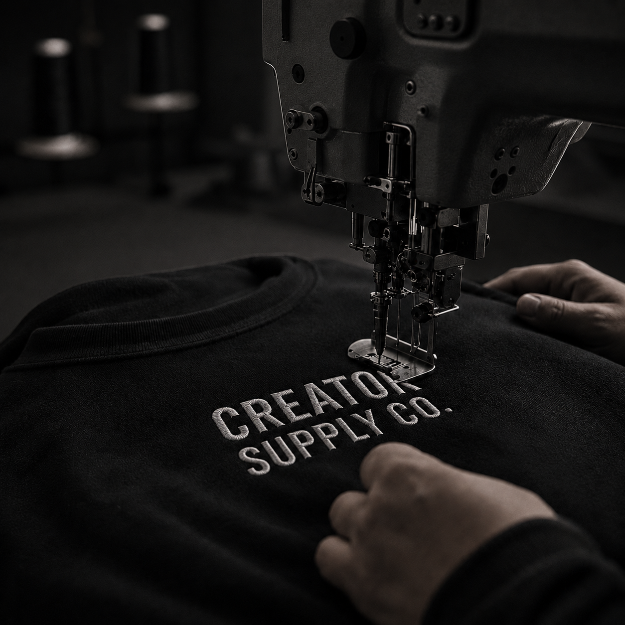 Embroidery machine stitching the Creator Supply logo on a black sweatshirt